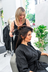 Hairdresser using curling iron styling client's hair in salon
