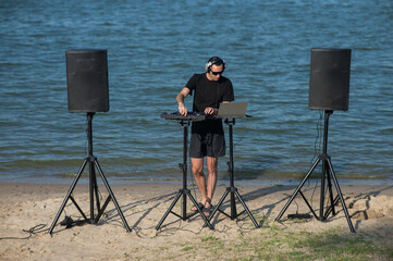 Caucasian man works as a DJ on the beach. 