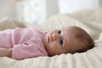 Cute newborn baby lying on bed indoors
