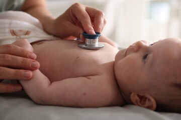 Pediatrician examining baby with stethoscope at table in clinic, closeup