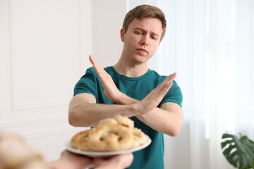 Gluten free diet. Man refusing from pastries indoors, selective focus