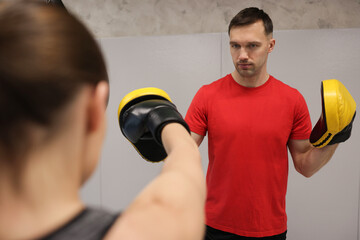 Young woman exercising with professional personal trainer in gym, closeup