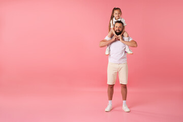 Family. Happy father and his daughter on pink background. Space for text