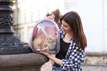Woman with her cute cat in backpack carrier on city street