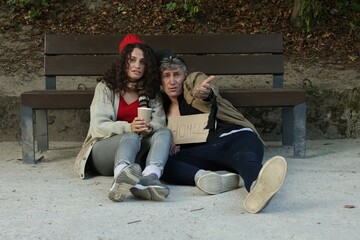 Homeless people begging for money near bench in park