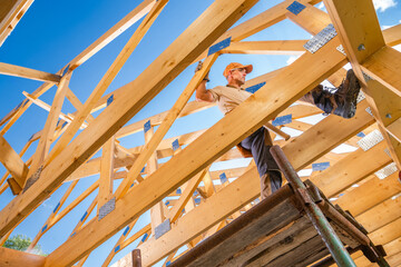 Construction Worker Balancing on Wooden Beams at a Building Site During Daylight Hours