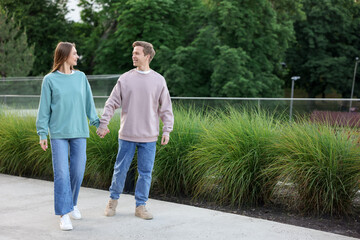 Lovely couple walking together on city street, space for text