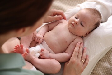 Mother putting her cute newborn baby to sleep on bed at home, above view
