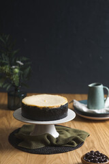 Homemade cheesecake on a chocolate cookie crust, elegantly displayed with a ceramic jug of hot chocolate in the background.