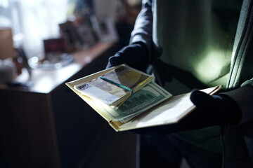 Man wearing gloves holding stack of euro and dollar banknotes in hands indoors, counting money with...