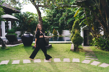 Joyful woman laughs while chatting on smartphone, barefoot indoors, in bright natural...