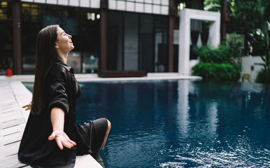 Woman with arms wide open facing sky by pool, embracing moment of clarity, joy and liberation from...