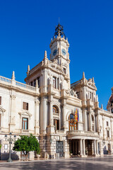 Obraz premium The City Hall in Alicante, showcasing intricate architecture with a prominent clock tower, standing under a clear blue sky, represents local governance and cultural heritage.