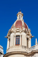 Fototapeta premium A close-up view of a historic building's ornate dome in Plaza del Ayuntamiento, showcasing intricate architectural designs under a clear blue sky. Perfect for travel and architecture themes.