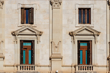 Close-up of an architectural facade featuring ornate stone carvings and wooden windows in Valencia,...