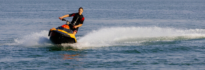 Young man speeds on a jet ski under the bright summer sun. Concept freedom, adrenaline, and water...