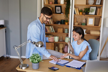 A couple engages in a lively discussion at a stylish home office, sipping drinks while sharing...