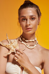 Summer vibes exude from the young woman with seashell jewelry in a studio setting