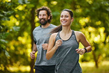 In a serene park, a man and woman run together during the early morning, relishing the fresh air...