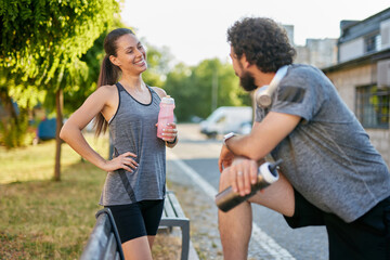 Two friends enjoy a relaxed moment after exercising, exchanging smiles and discussing their fitness...