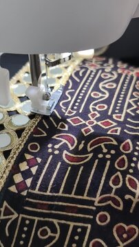 Mirror work embroidery is getting stitched on ajrak print fabric on a sewing machine, showcasing traditional Indian textile craftsmanship and precision tailoring. Chaniya choli in making for navratri 