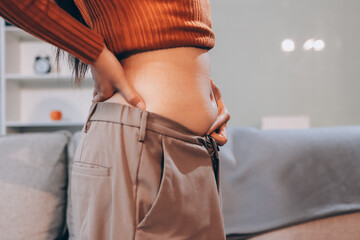 woman's hand holding excessive belly fat, overweight concept