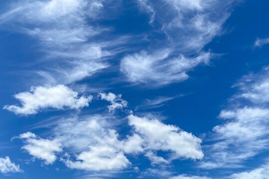 View looking up at a bright blue sky with wispy and fluffy clouds on a bright sunny day