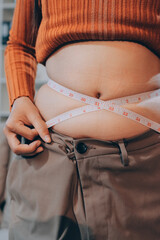 woman's hand holding excessive belly fat, overweight concept