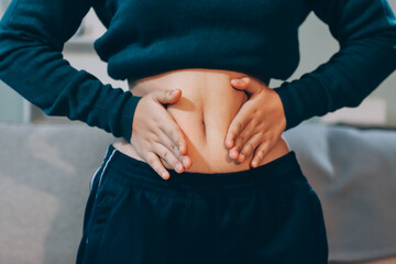 woman's hand holding excessive belly fat, overweight concept
