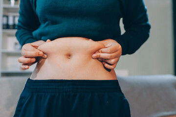 woman's hand holding excessive belly fat, overweight concept