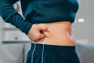 woman's hand holding excessive belly fat, overweight concept