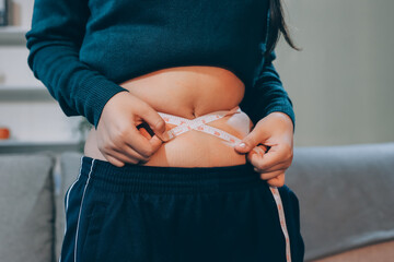 woman's hand holding excessive belly fat, overweight concept