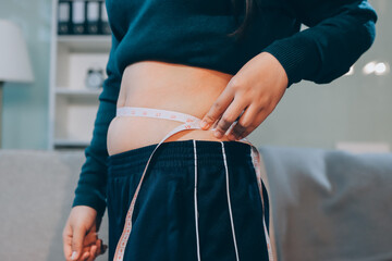 woman's hand holding excessive belly fat, overweight concept