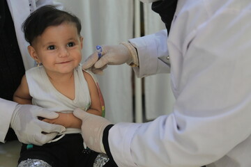 A doctor examines children's malnutrition inside a refugee camp. Malnutrition was measured using a mid-upper arm circumference belt.