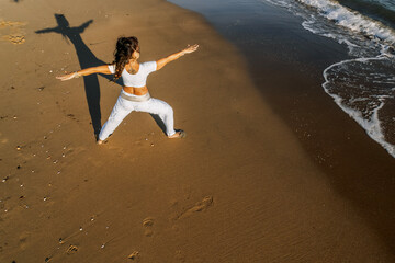 Woman Practicing Warrior Pose on Beach at Sunset