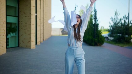 A woman arms raised high, celebrates the successful completion of a project, as papers flutter around her. A woman, radiating happiness sending papers dancing in the breeze. - Powered by Adobe