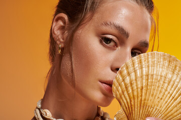 Young woman showcases summer elegance with seashell necklace in vibrant studio setting