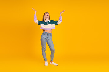 Young stylish woman gesturing energetically in a casual outfit on a yellow background, expressing joy and confidence in a modern lifestyle