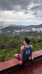 Handsome Man Relaxing on Holiday with Lush Green Valley and Misty Mountain Views