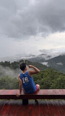 Handsome Man Relaxing on Holiday with Lush Green Valley and Misty Mountain Views