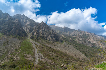 Ala-Archa Park, Steep rugged mountains rise, lush valleys, rocky terrain and grassy patches, vibrant sky, inviting trekkers, climbers, hikers and adventurers to explore pristine alpine wilderness