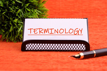 TERMINOLOGY text written on a white card on a stand on an orange background
