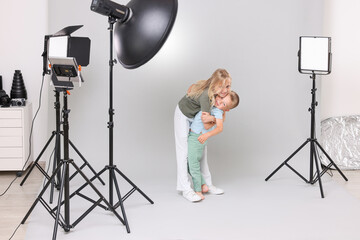 Little girl and her brother on light grey background in photo studio with professional equipment