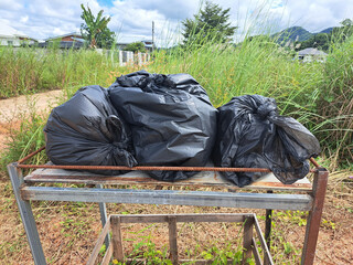Black Garbage Bags Placed Outdoors on a Metal Frame Platform in a Grassy Area