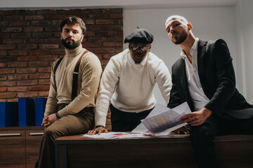 Three diverse professionals engage in a discussion around printed documents in a modern office....