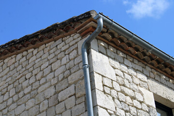 Gouttière en zinc gris sur le mur en pierre