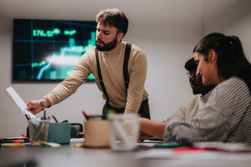Professionals collaborating at a desk while discussing business data in an office environment. A...