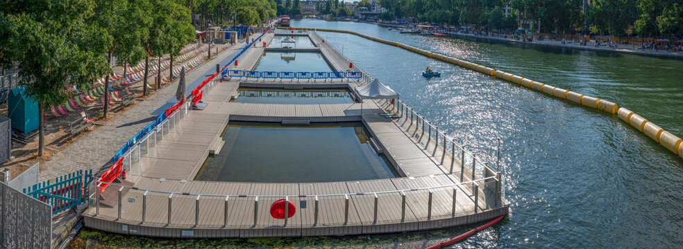 Paris, France - 07 19 2025: Paris Beach, Bassin de la Villette. Panoramic view of the oudoor swiming pool and the instalations along the quays during Paris Beach in summer