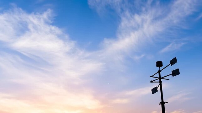 Weather station with wind vane and anemometer under blue sky and soft clouds at sunset capturing calm peaceful atmosphere