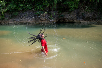 A man shaking his hair in the water, Playing splashing with his hair in the river, Photo from the side